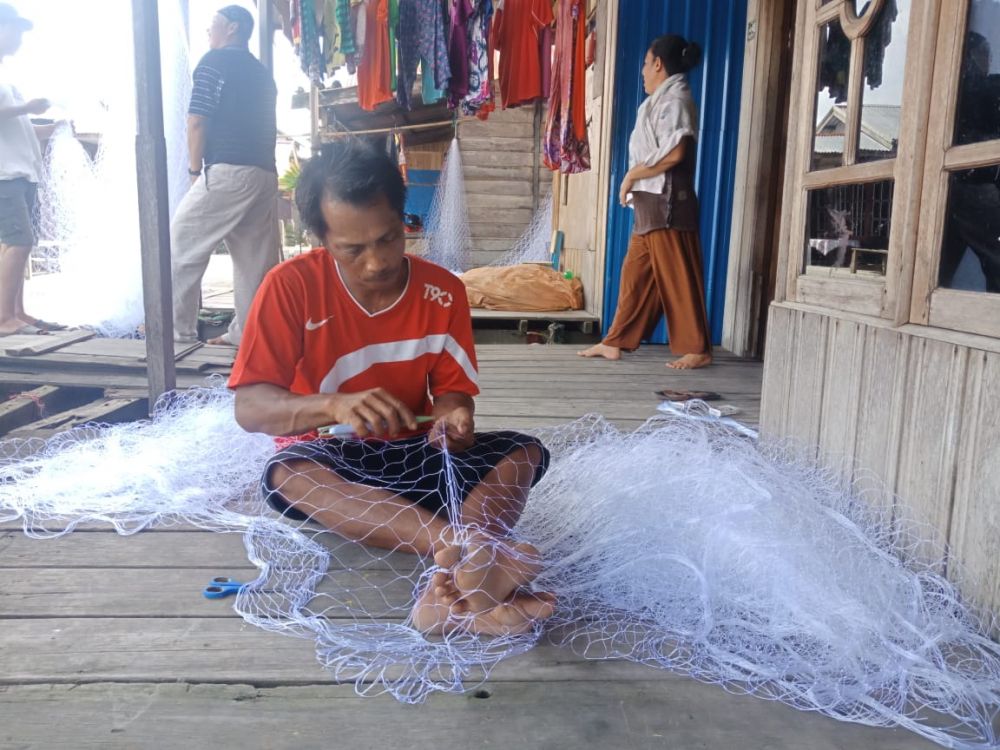 Salahsatu Nelayan sedang merajut jaring untuk tangkap ikan