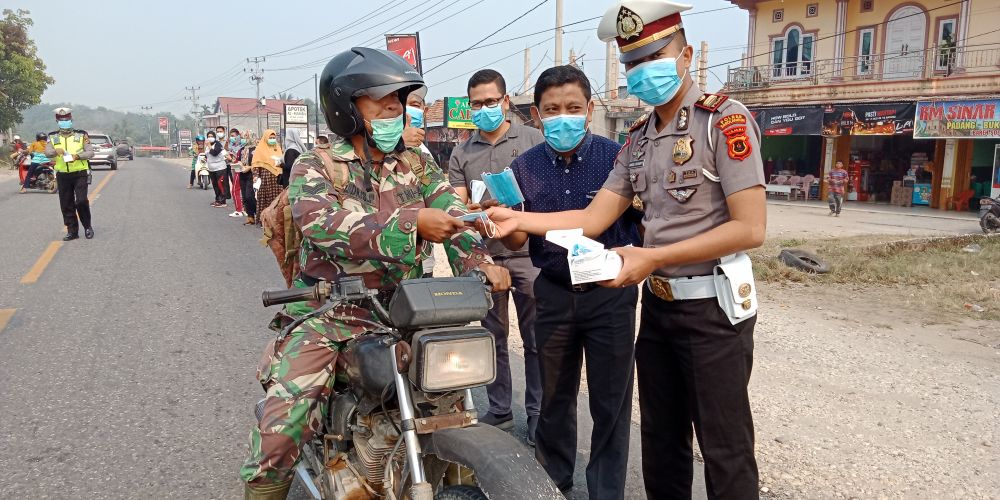 Direktur RSUD CQ, dr Bambang Hermanto dan Kasat Lantas Polres Sarolangun, Iptu Angga Luvyanto sedang memberikan masker kepada anggota TNI yang sedang melintasi Jalinsum, Kecamatan Pelawan.