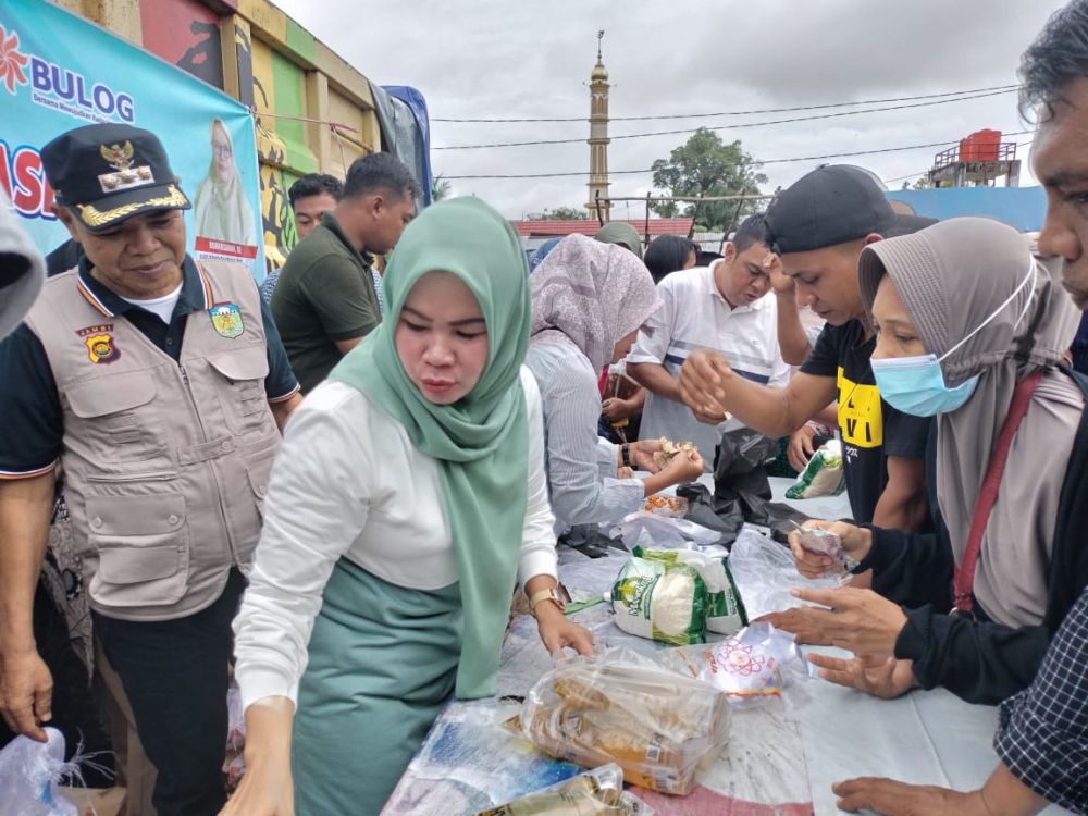 PJ Bupati Tebo bersama istri terlihat sibuk melayani masyarakat yang menyerbu operasi pasar yang digelar Pemkab Tebo