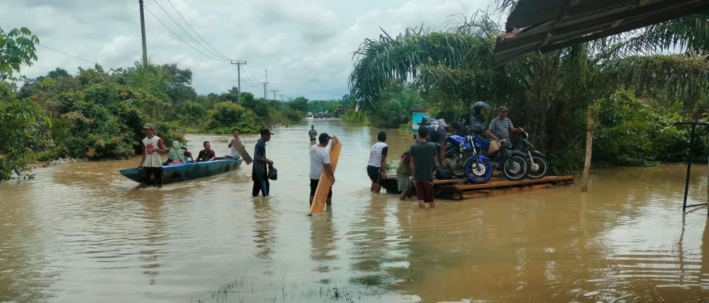Warga terpaksa menggunakan rakit untuk menyebrangi jalan yang terendam banjir menuju jembatan penampuyan di Bungkal Kelurahan Muaro Tebo