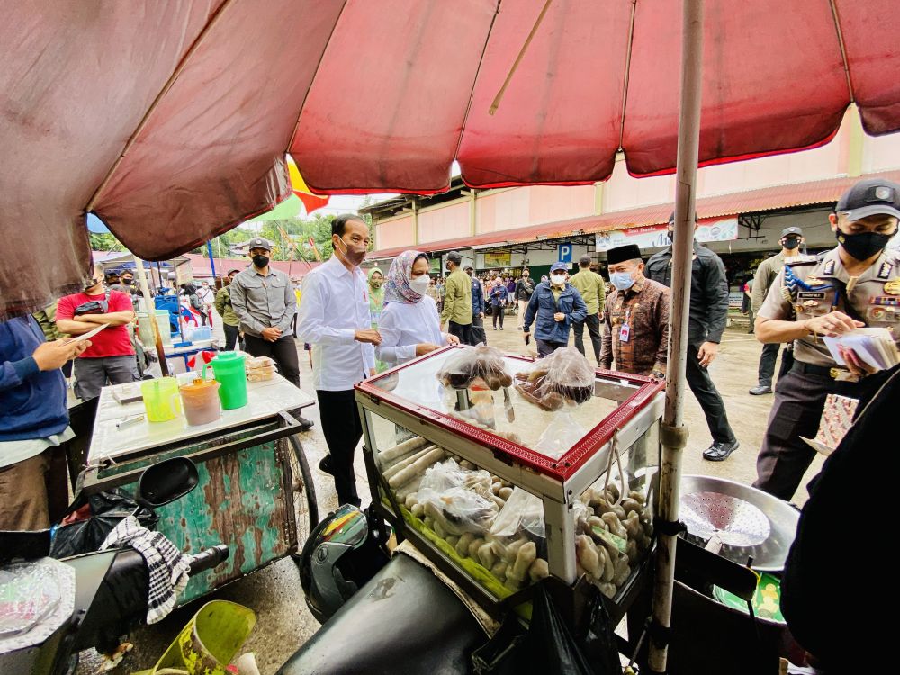Presiden Joko Widodo (kedua kiri) didampingi Ibu Negara Iriana Joko Widodo (kedua kanan) berbincang dengan pedagang makanan saat kunjungan kerja ke Pasar Modern Angso Duo di Jambi, Kamis (7/4/2022)