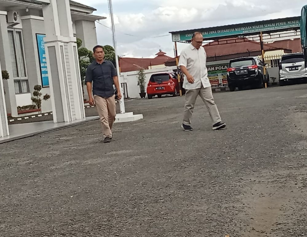 Tampak Ak memakai kemeja hitam  dan HP kemeja putih saat keluar dari kantor Kejari Sungaipenuh, Rabu(15/02/2022).